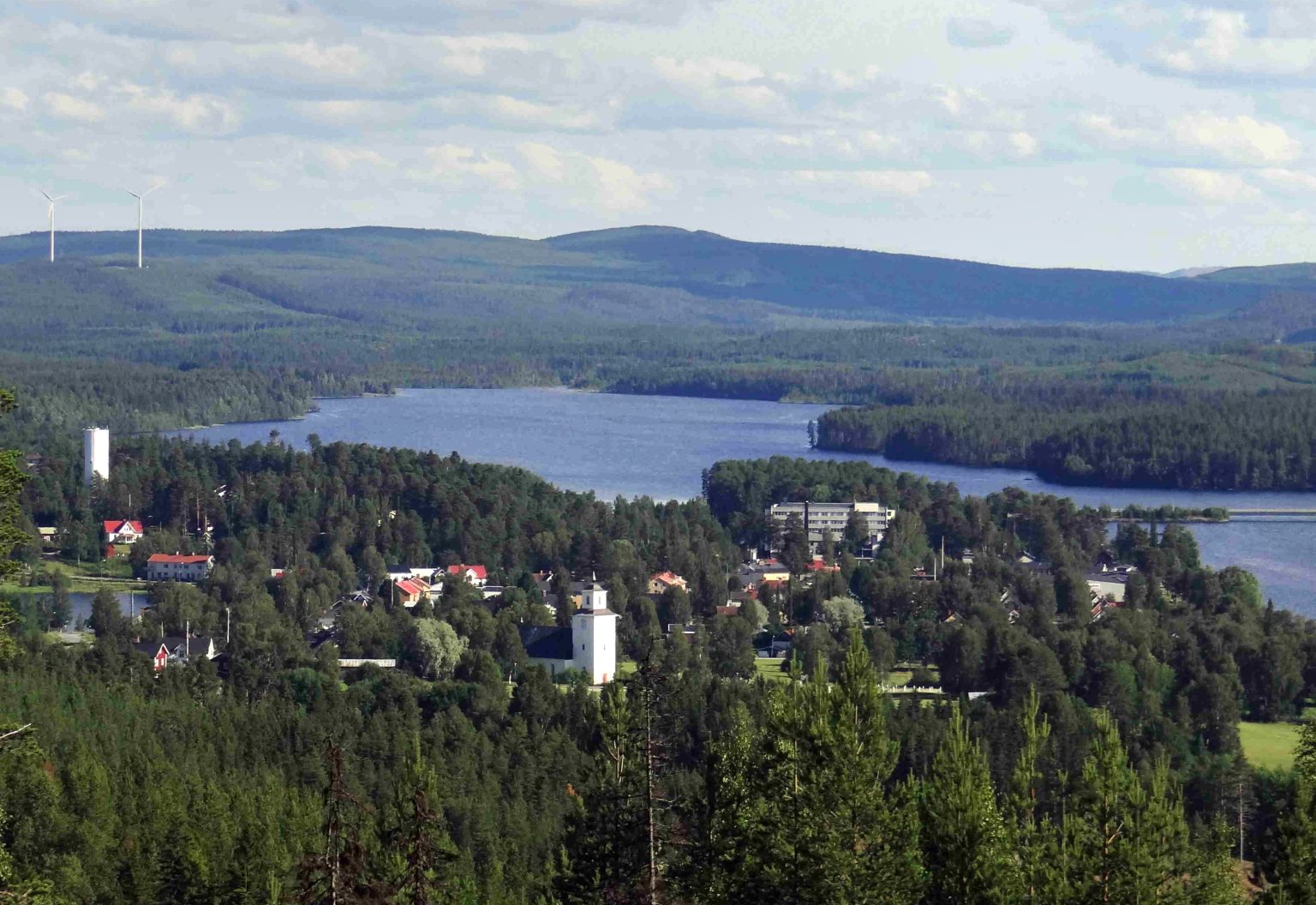 Drönarvy över Backe med skog och sjöar i fjärran.